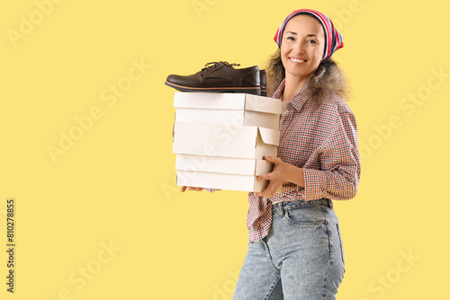 Female shoemaker with boxes on yellow background