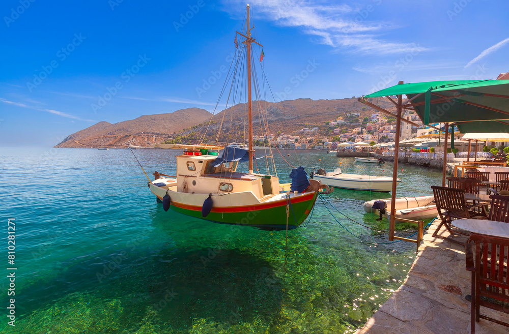 Serene harbor view with a traditional fishing boat on Symi Island, Greece