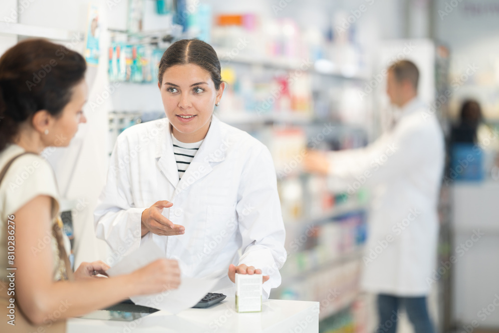 Kind female druggist giving advice to woman client buying medicine in pharmacy store