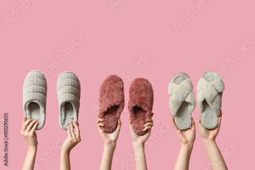 Female hands holding different women's slippers on pink background