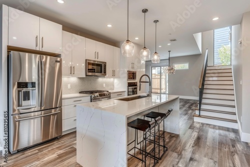 Bright and spacious modern kitchen design featuring stainless steel appliances  white cabinets  a kitchen island  and elegant pendant lighting