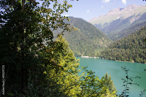 Bright turquoise lake Ritsa in Abkhazia among green hills on a sunny summer day