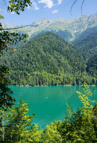 Bright turquoise lake Ritsa in Abkhazia among green hills on a sunny summer day