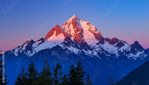 As twilight descends, the majestic mountain peak stands out with its snow-capped grandeur against the dusky blue sky