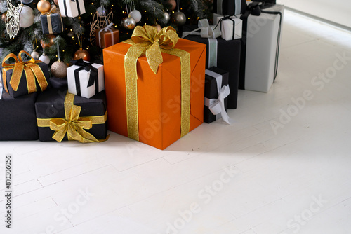 Christmas present gift box stacked close up. Holiday sale concept. Many gift box black, white, orange color with gold ribbon and light garland