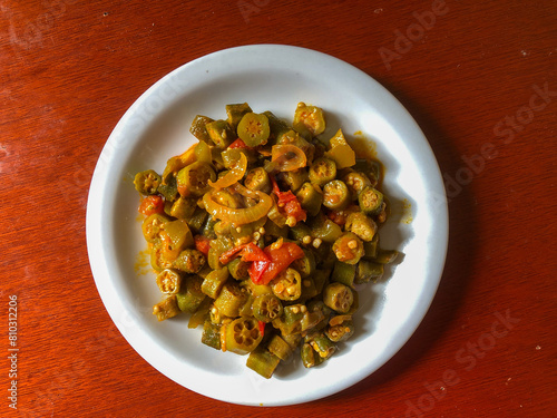 Delicious cooked okra with tomato sauce served on a porcelain plate photo