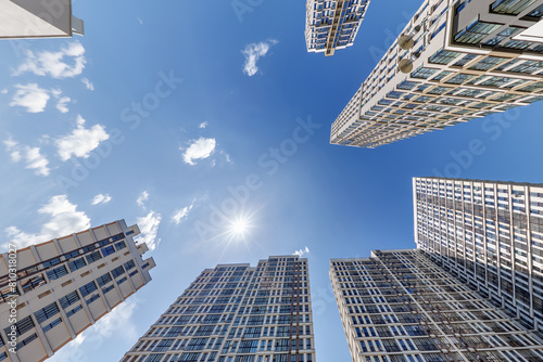 view from below into blue sky with clouds of large modern skyscraper residential complex