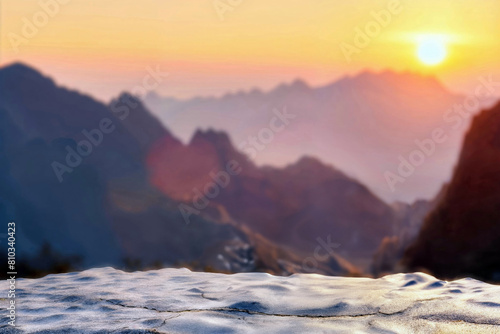 Sunset over mountain peaks with a blurred foreground of a rocky surface. High quality photo