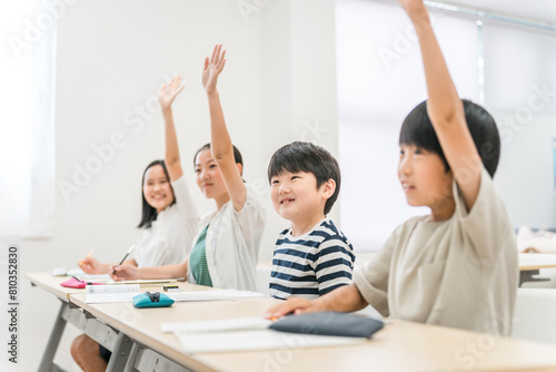 塾・学校の授業中に元気に挙手する小学生の男女生徒
 photo