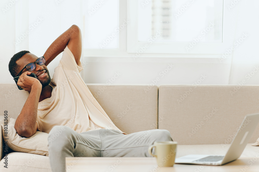 Smiling African American Man Working on Laptop and Talking on Phone in Cozy Home Office Smiling African American Man Working on Laptop and Talking on Phone in Cozy Home Office