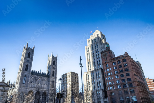Notre Dame Basilica in the Old Montreal and its iconic towers, with the Aldred Building in backgground. The basilica is the main cathedral of Montreal, and a touristic landmark. photo