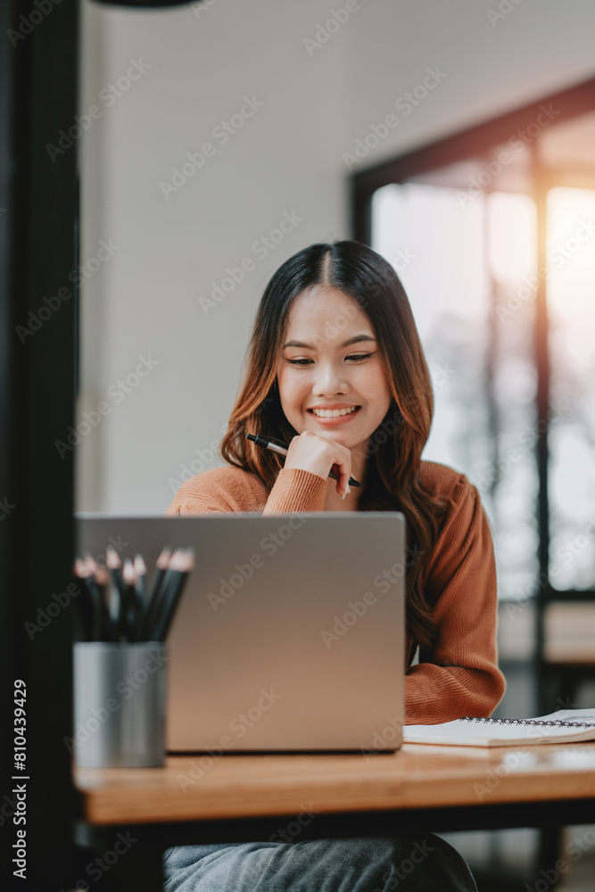 Smiling young female professional deeply focused on her laptop screen, working in a bright, modern office setting. Smiling young female professional deeply focused on her laptop screen, working in a bright, modern office setting.