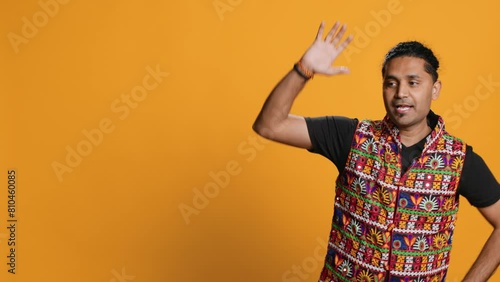 Smiling person having fun, dancing on rhythm, enjoying relaxation time. Jolly indian man goofing around, entertaining himself doing funky movements, isolated over studio background, camera A photo