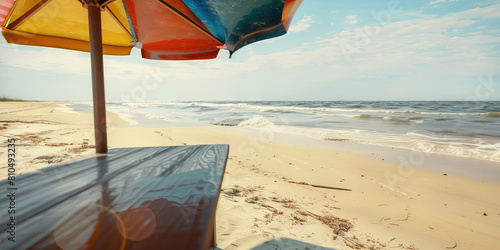 Padre Island Productivity: A sunny beachside desk underneath a colorful beach umbrella, with waves gently lapping in the distance.