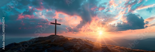 cross on top of a mountain with a sunset in the background