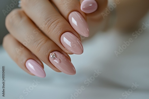 a woman s hand with a pink manicure and a diamond on fingernail