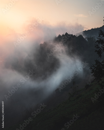 Clouds swirling into a mountain valley at sunset.