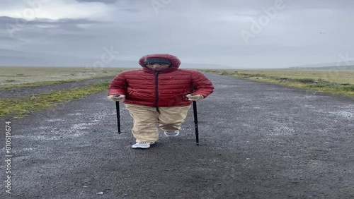 Adult woman walking in the rain on a dirt road in the mountains, the camera rotates around the subject in high definition 4K at 60fps