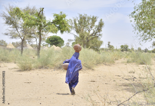 Valokuva Pakistan women crossing sand dunes and carrying on their heads water from local