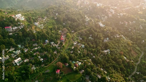 Aerial drone train snaking through Ella, Sri Lanka, in terraced farms, dense forest. Sunset bathes tropical landscape, revealing cozy hotels, thriving gardensa traveler paradise. photo