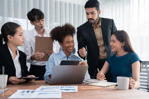 Multiracial analyst team use BI dashboard data to analyze financial report on meeting table. Group of diverse business people utilize data analysis by FIntech for success business marketing. Concord