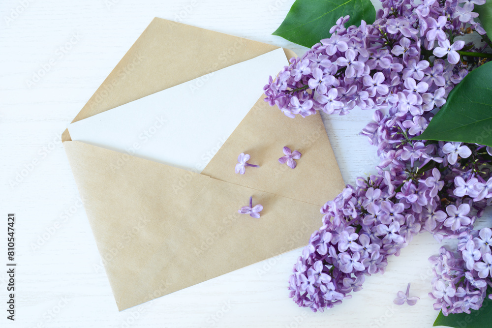 Bouquet of lilac flowers and open paper envelope on white wooden background, top view, copy space, flat lay Bouquet of lilac flowers and open paper envelope on white wooden background, top view, copy space, flat lay
