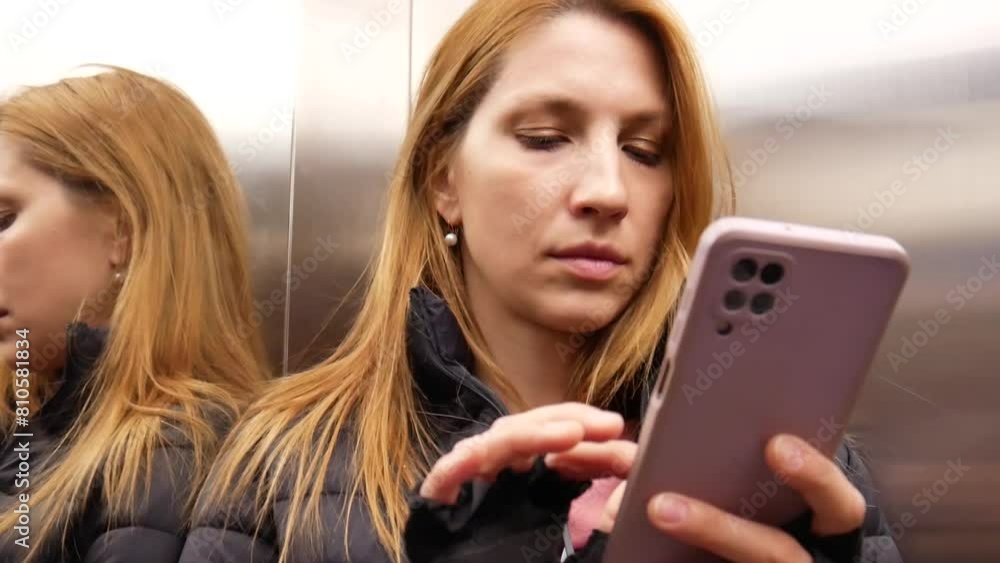 A beautiful woman using a smartphone while in elevator close-up A beautiful woman using a smartphone while in elevator close-up