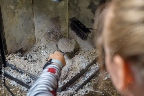 Cleaning the fireplace. Ash and charred piece of wood lying on the blade with a long handle closeup