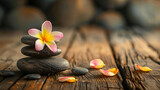 Spa stones with beautiful flower on wooden background