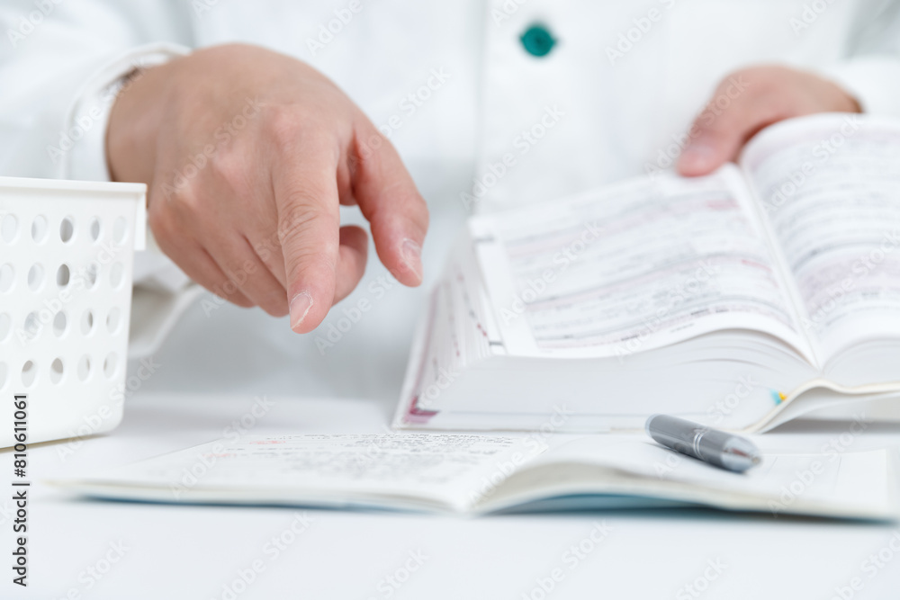 Foto お薬手帳の薬をマニュアルを見て安全確認をする薬剤師の手元