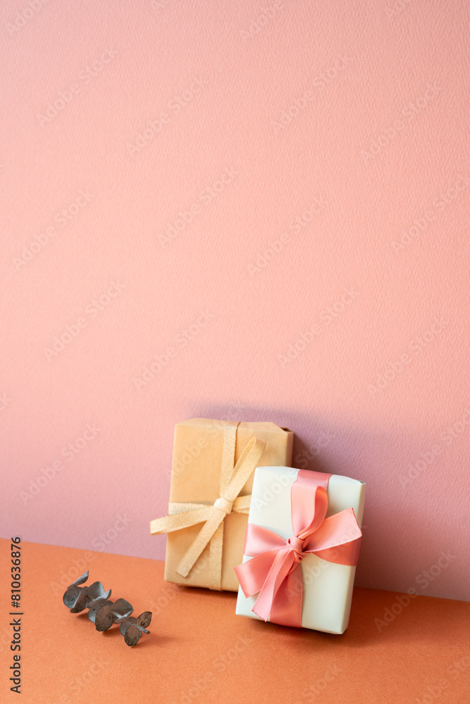 Gift boxes and eucalyptus leaf on orange table. pink wall background with copy space