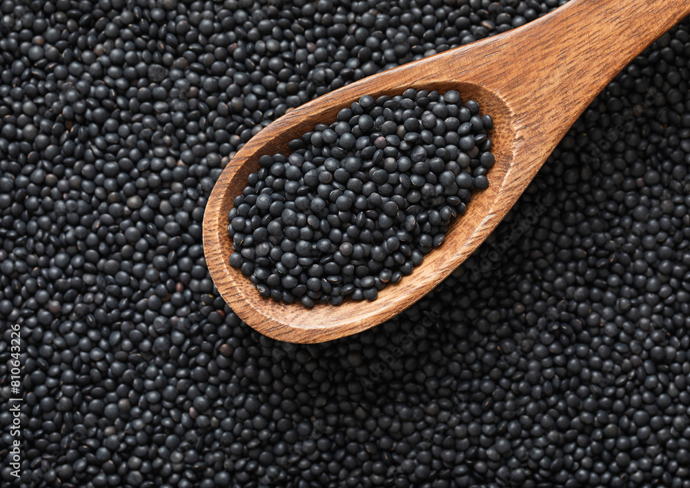 Wooden spoon of black organic healthy lentils grain seed.Macro. Wooden spoon of black organic healthy lentils grain seed.Macro.