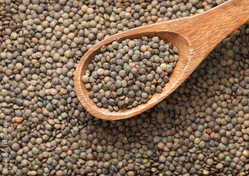 Green raw healthy organic lentils grain seeds on wooden spoon in kitchen.Macro.