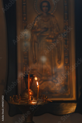 The icon of Panteleimon the Healer hangs on the wall in the temple. Church candlestick with burning candles
