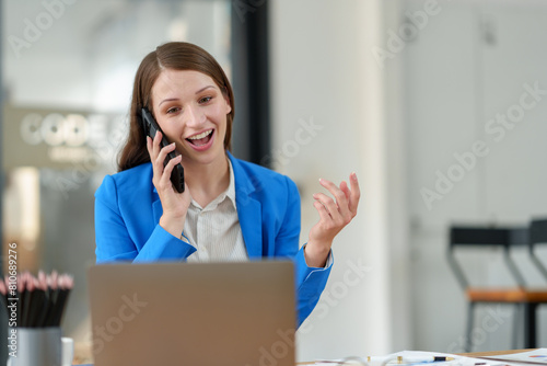 African businesswoman American uses smartphone while working on laptop at office Businesswoman working on the phone online applications Success concept, relaxation, online ordering.
