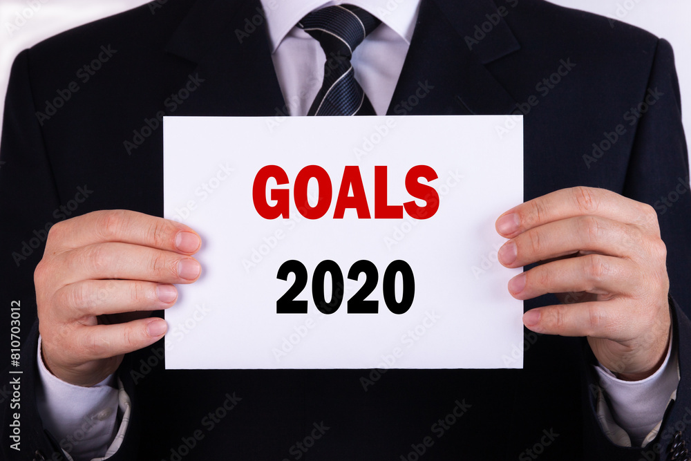 Businessman holding a card with text goals 2020 Businessman holding a card with text goals 2020