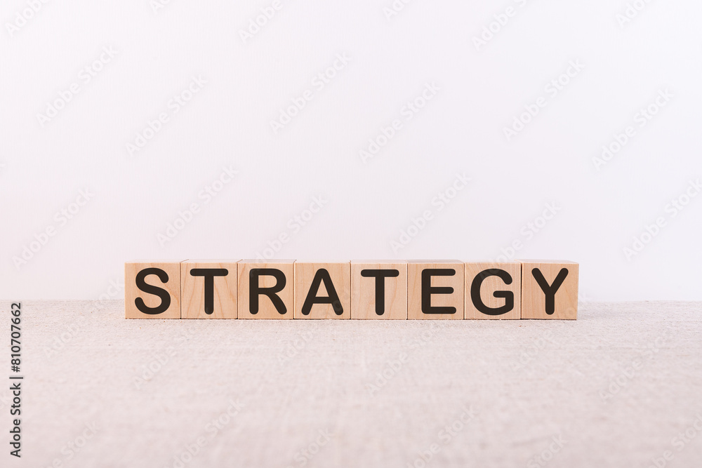 STRATEGY word concept written on wooden cubes lying on a light table and light background. STRATEGY word concept written on wooden cubes lying on a light table and light background.