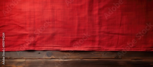 An old wooden table is shown from above with a vibrant red tablecloth leaving an empty space for adding an image. Creative banner. Copyspace image