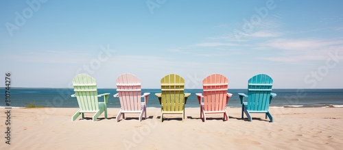 There are empty Adirondack chairs placed on the sandy beach creating a visually appealing copy space image