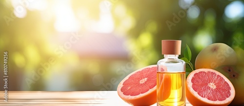 Close up photo of grapefruit essential oil in a bottle alongside a fresh fruit placed on a well lit table There is empty space available for adding text. Creative banner. Copyspace image photo