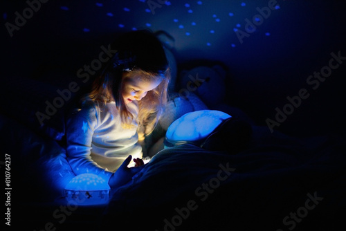 Little girl reading a book in bed