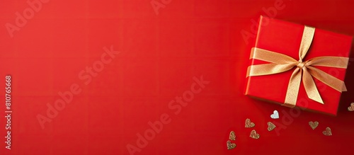 A top down view of a gift box placed on a vibrant red background with plenty of room around it for adding text or other elements This image symbolizes love and joyful celebrations. Creative banner