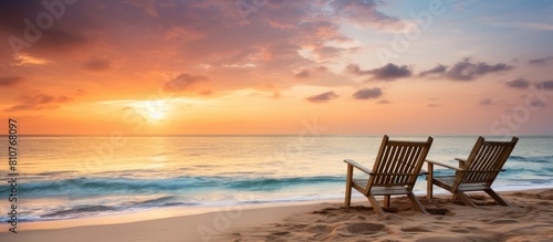 A serene and peaceful beach scene at sunrise featuring a pair of empty loungers placed by the coast embodies the ideal image for a dream vacation The soothing ambiance and the beauty of the untouched © HN Works