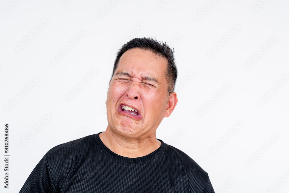 A middle aged Asian man grimaces with a yuck facial expression after tasting something bitter, against a white background. A middle aged Asian man grimaces with a yuck facial expression after tasting something bitter, against a white background.