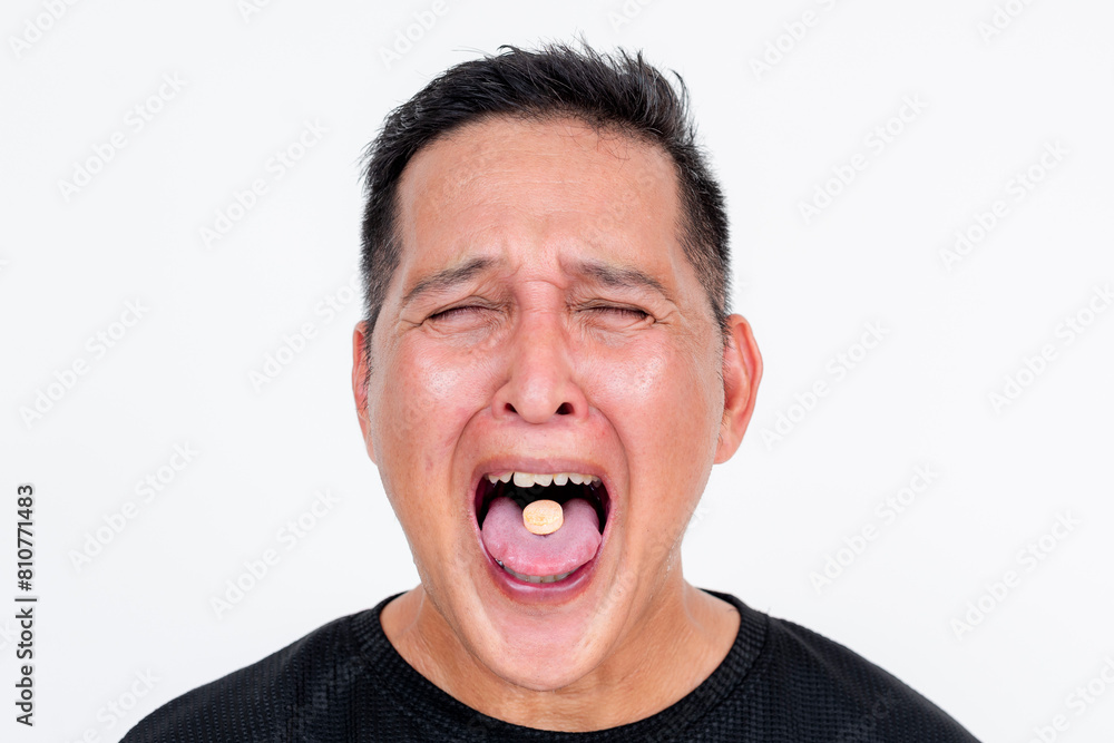 Middle-aged Asian man grimacing while taking bitter medicine, isolated on white Middle-aged Asian man grimacing while taking bitter medicine, isolated on white