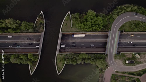 Steady top down aerial view of submerged highway with traffic passing underneath Veluwemeer aquaduct seen from above. Dutch waterway infrastructure for boats to pass over freeway with traversing road photo