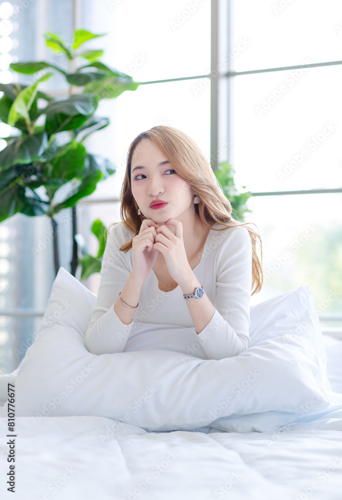 Asian beautiful woman in her bedroom on bed, feeling happy and smiling relaxed stretching arm and body after getting up from sleep on bed in bedroom at home, waking up in the morning. Asian beautiful woman in her bedroom on bed, feeling happy and smiling relaxed stretching arm and body after getting up from sleep on bed in bedroom at home, waking up in the morning.