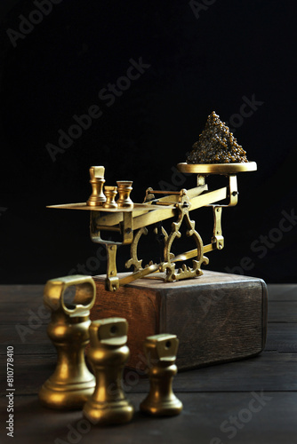 Black caviar on the scales. Vintage brass scales are out of focus. An exquisite and expensive snack. Natural omega. Dark background. Vertical photo.