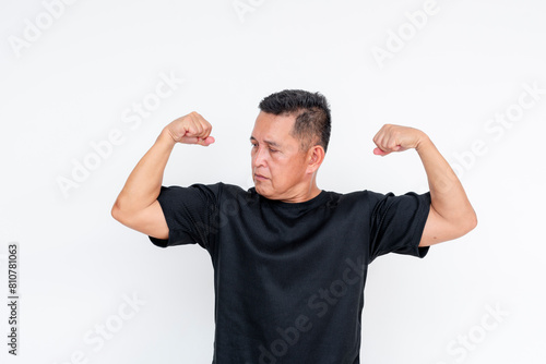 Confident middle-aged Asian man flexing biceps, isolated on white © Mdv Edwards