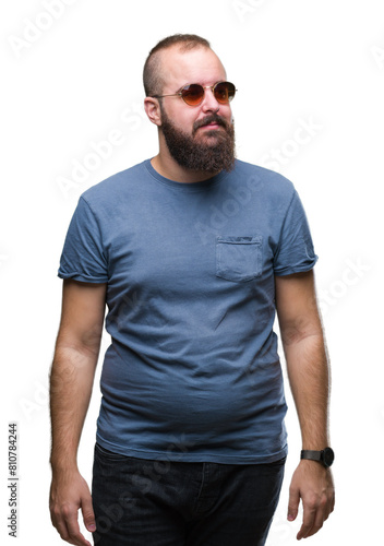 Young caucasian hipster man wearing sunglasses over isolated background looking away to side with smile on face, natural expression. Laughing confident. © Krakenimages.com